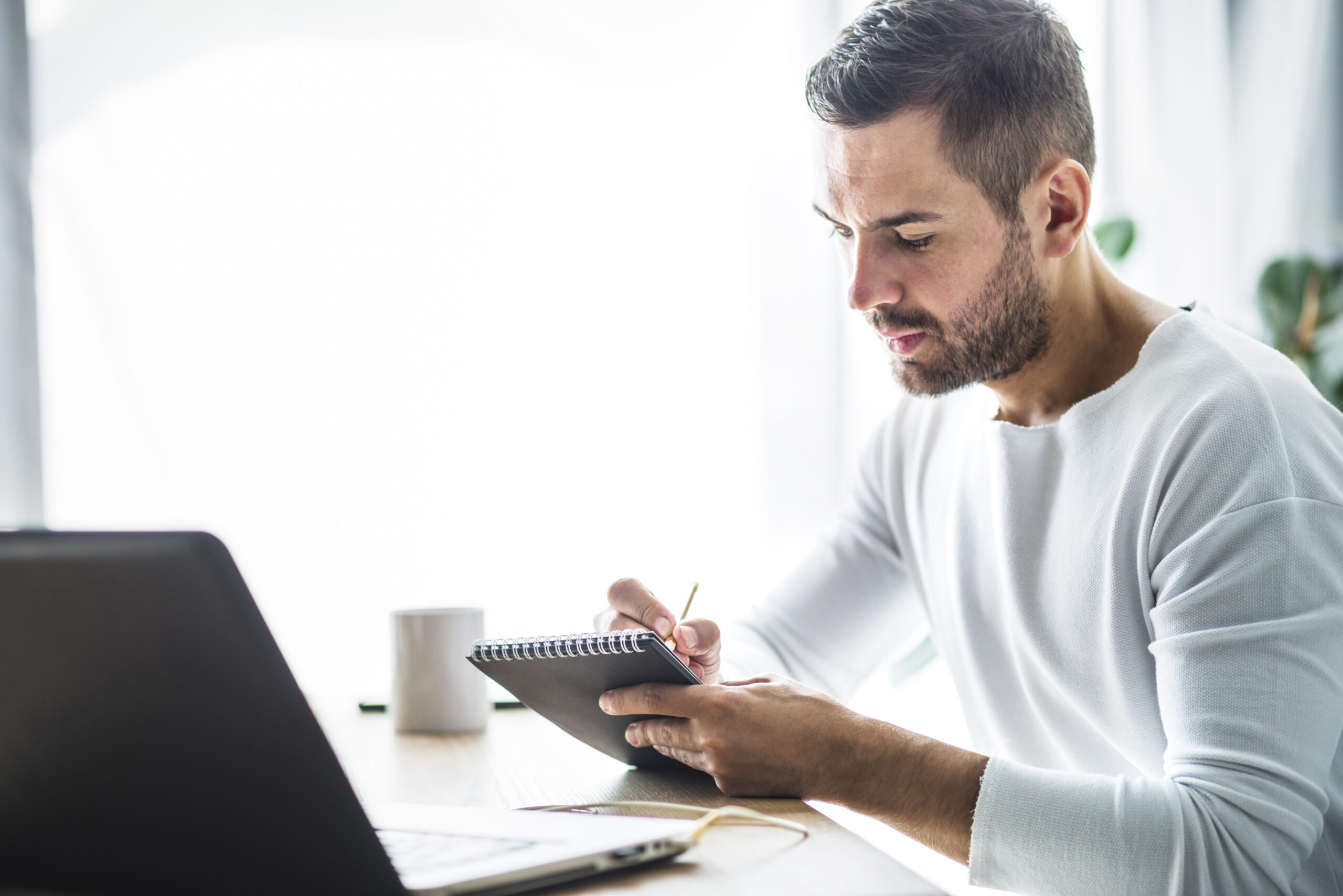 Homem em ambiente de trabalho analisando informações e fazendo anotações como parte do planejamento financeiro para 2026.