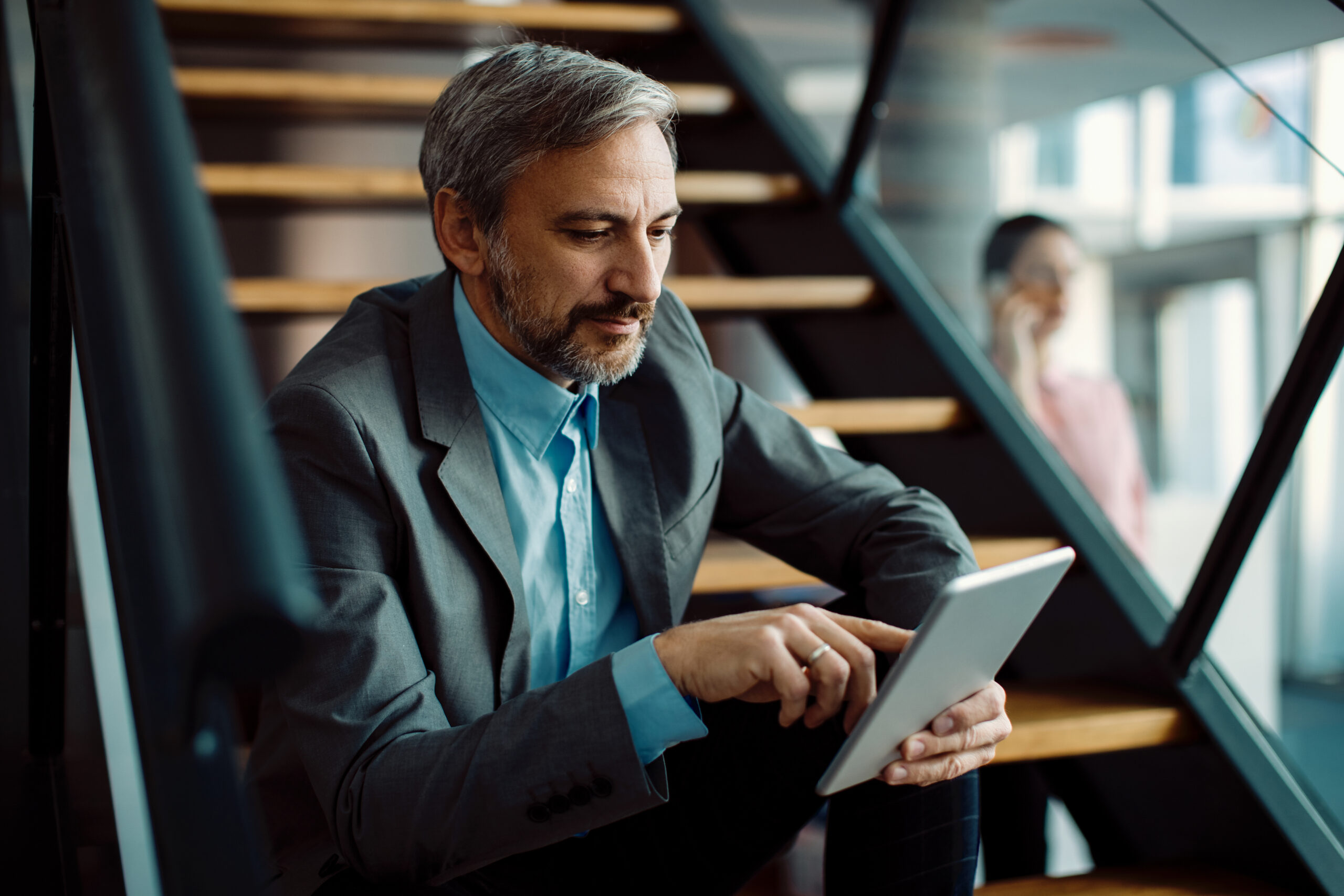 Man in a corporate setting using a tablet, representing digital information analysis, financial technology, and clear decision-making.